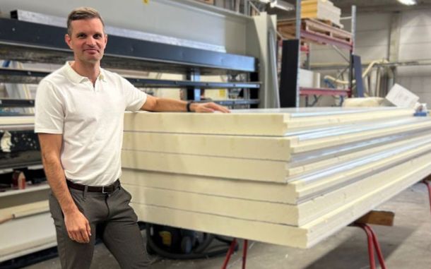person står vid kylpanel och tittar mot kameran